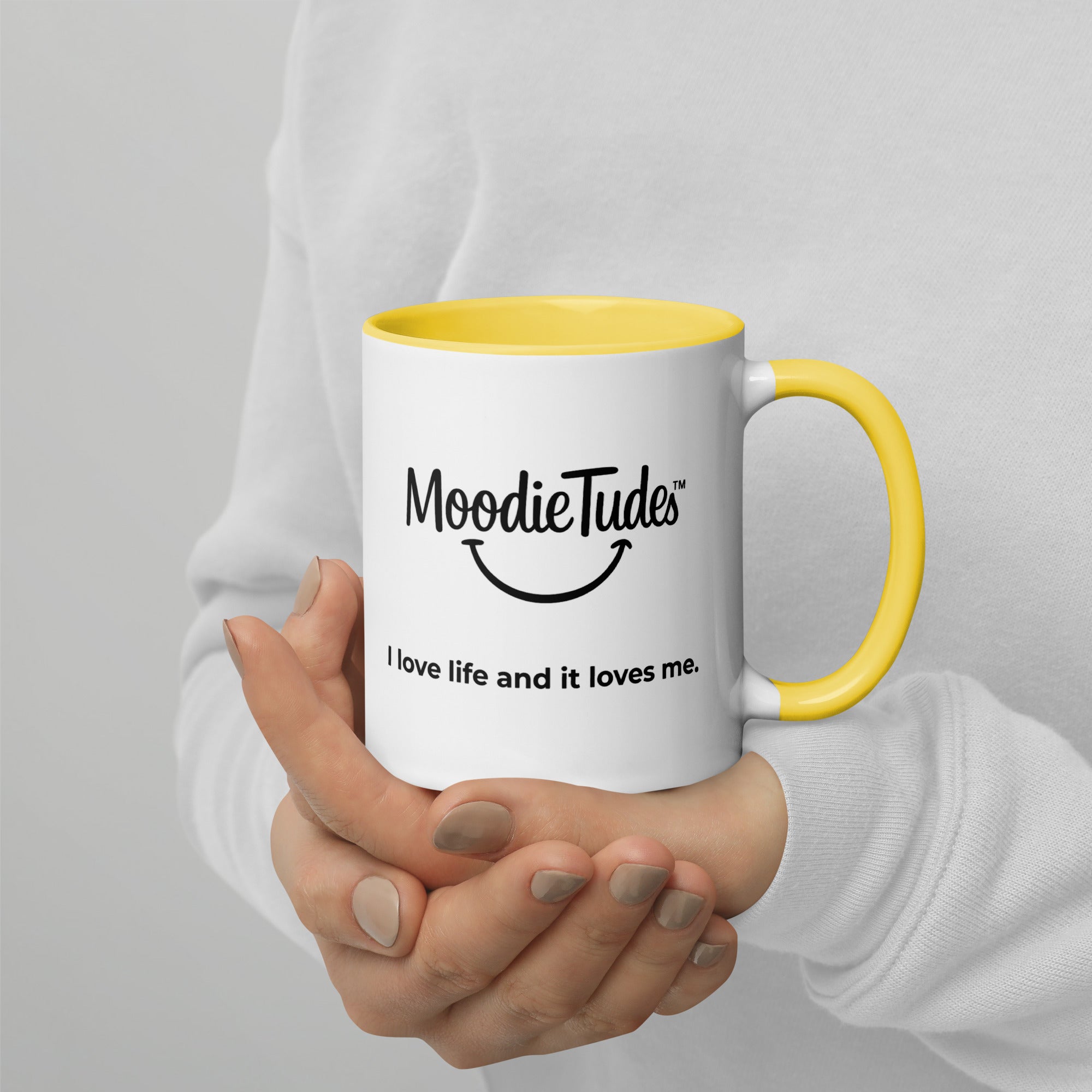MoodieTudes™ Radiant mug held in hand, logo and tag line visible